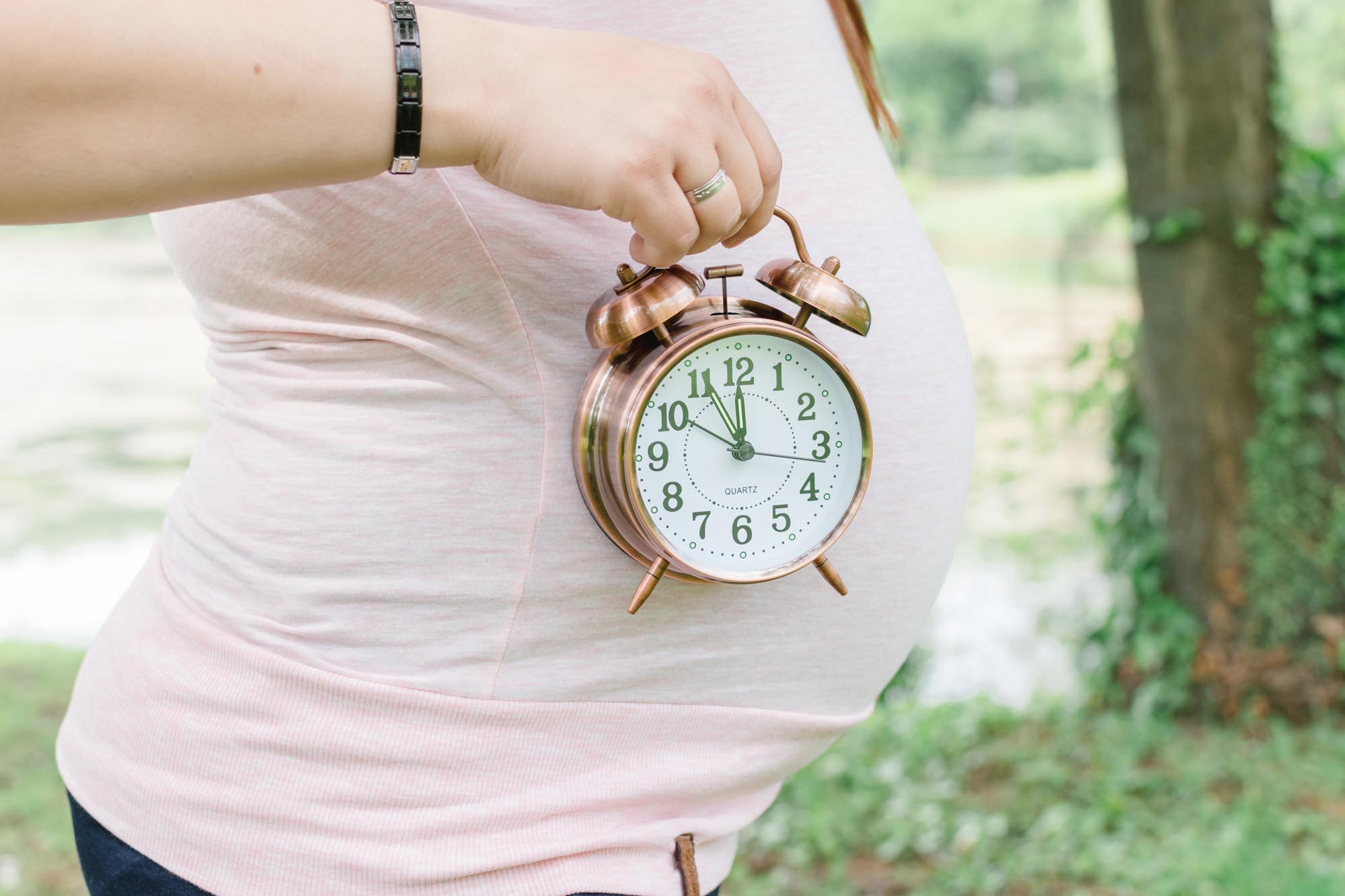Babybauch_Schwangerschaftsshooting_Mama hält Uhr seitlich vom Babybauch