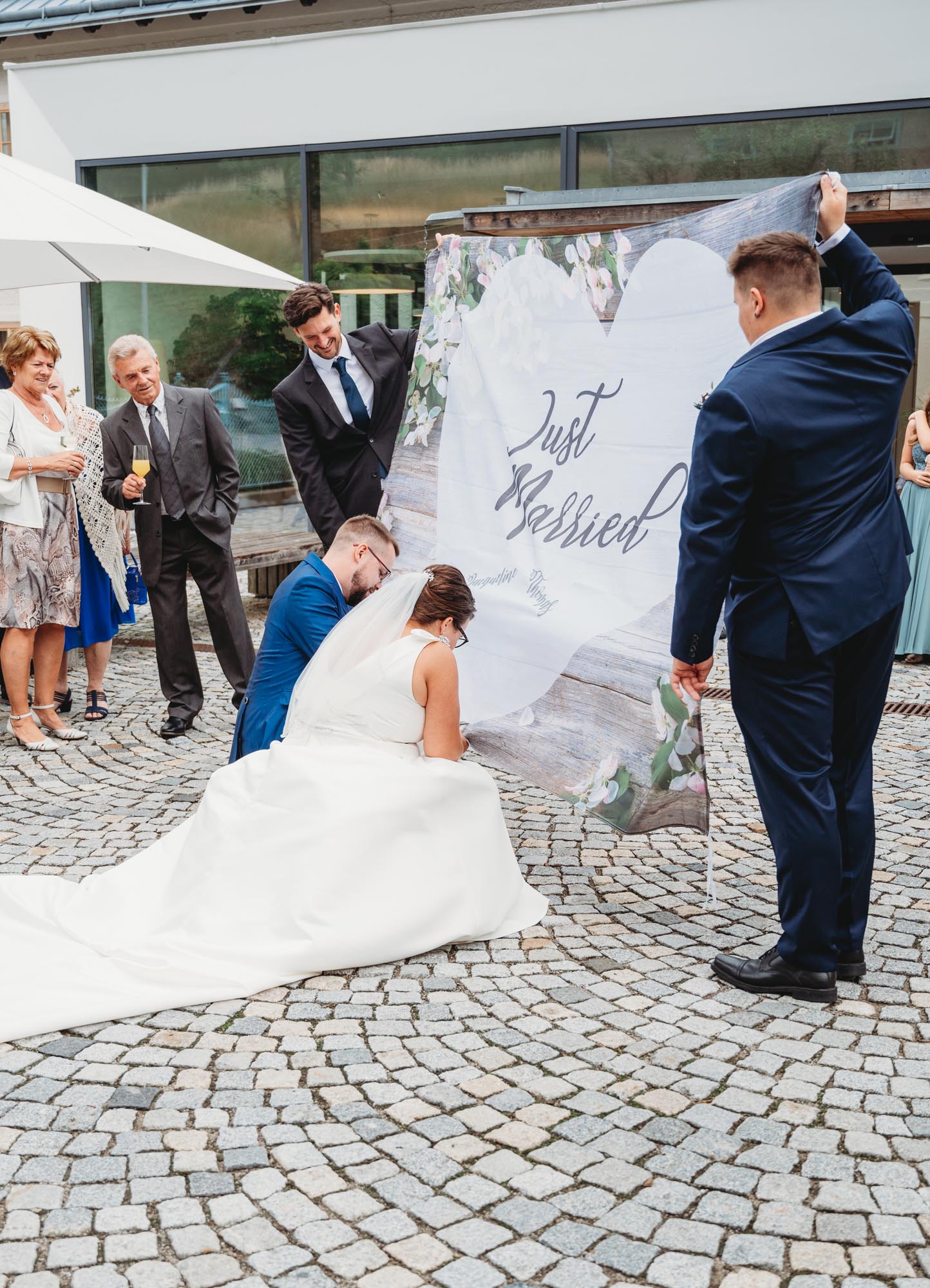 Hochzeitsfotos_Hochzeitsreportage in Wien_Feier_Brautpaar bekommt Aufgabe das Herz aus dem Tuch zu schneiden