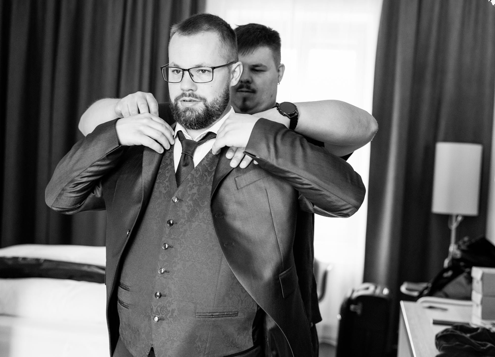 Hochzeitsfotos_Hochzeitsreportage in Wien_Getting Ready_Trauzeuge hilft Bräutigam beim Sakko anziehen