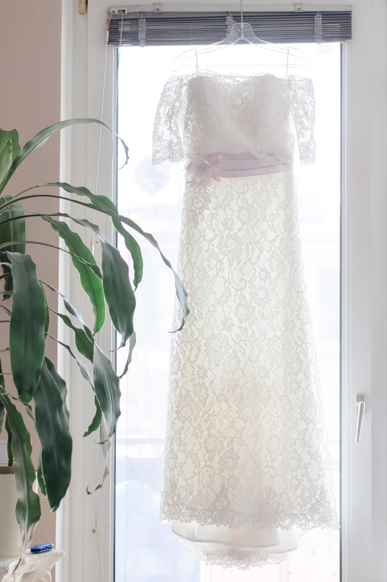 Hochzeitsfotos_Hochzeitsreportage in Wien_Brautkleid hängt im Fensterrahmen