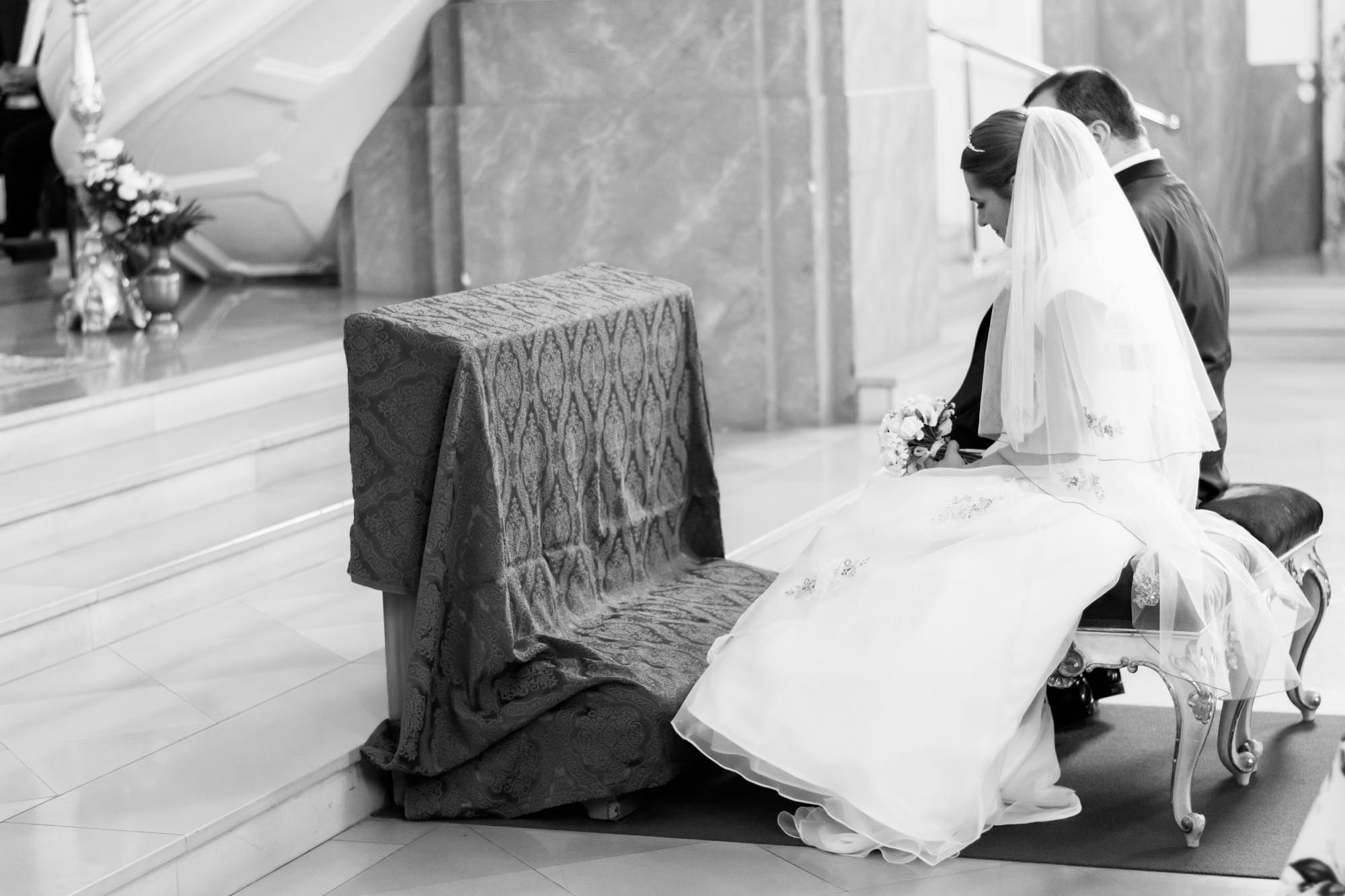 Hochzeitsfotos_Hochzeitsreportage in Wien_Kirche_Seitliche Aufnahme vom Brautpaar auf der Bank sitzend