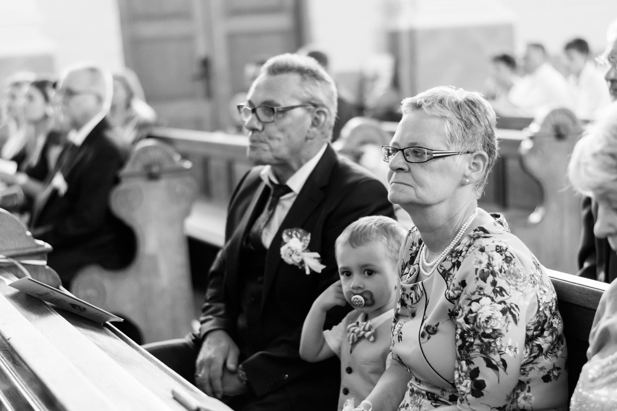 Hochzeitsfotos_Hochzeitsreportage in Wien_Kirche_Brauteltern lauschen gespannt derTrauung