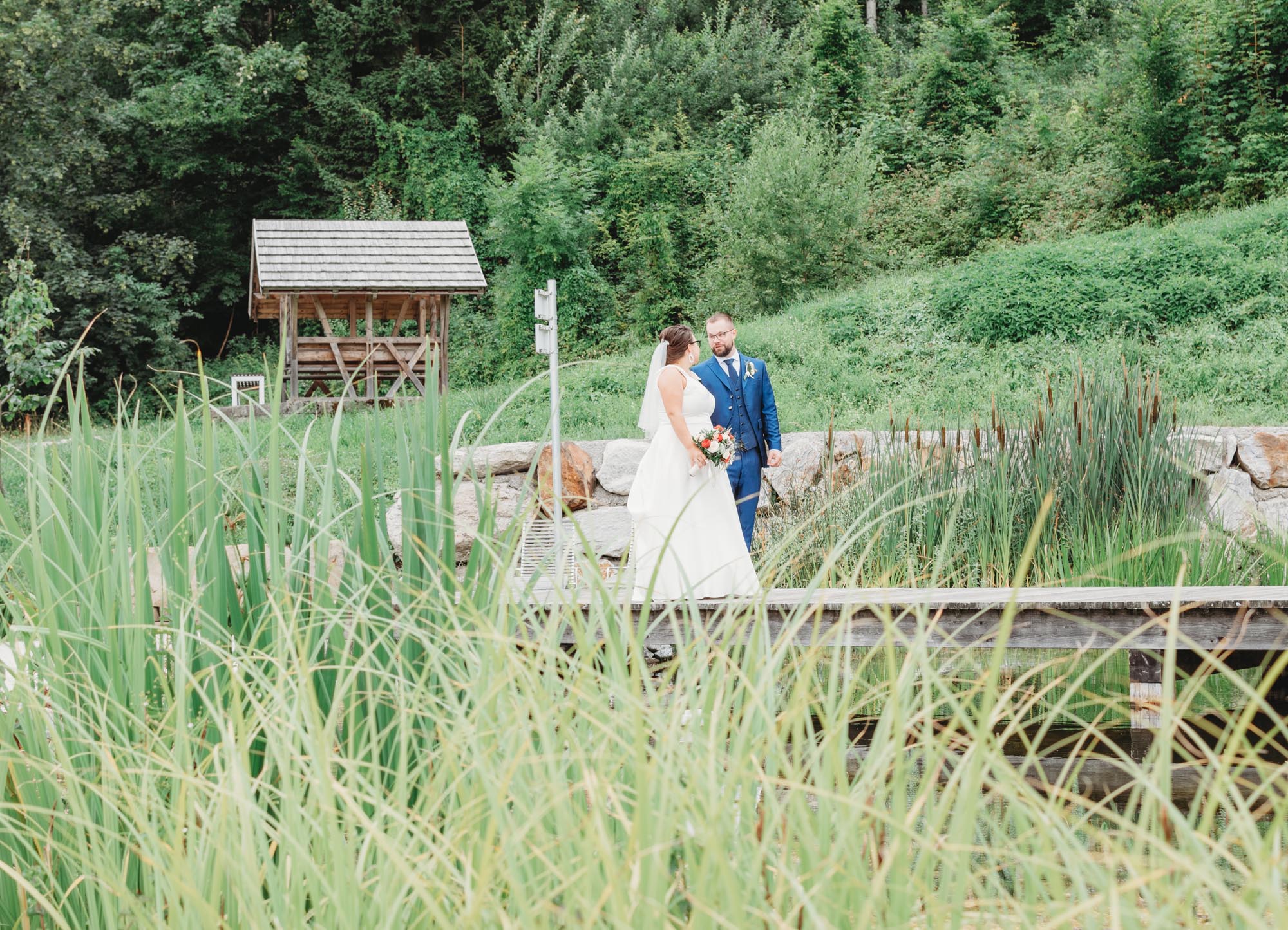 Hochzeitsfotos_Hochzeitsreportage in Wien_Brautpaarshooting_Brautpaar steht auf Steg bei Teich