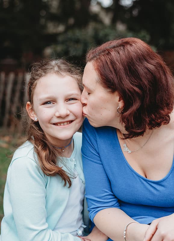 Mama gibt Tochter ein Bussi auf die Wange beim Muttertags-Fotoshooting in Wien
