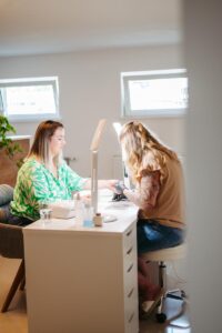 Businessreportage: Blick durch die Tür auf den Arbeitstisch der Nageldesignerin. Sie arbeitet grade mit ihrer Kundin