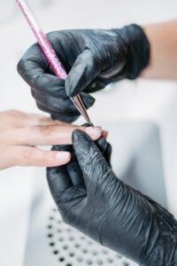 Businessreportage: Nageldesignerin trägt eine Schicht Glitzer-French auf