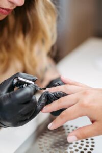 Businessreportage: Nageldesignerin trägt eine Schicht Gel auf den Nagel ihrer Kundin auf