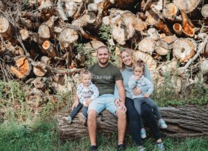 Familie. mit 2 Kindern sitzt auf einem Holzstamm in der Natur