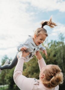 Oma spielt mit Enkelin und wirft sie bei in die Luft und fängt sie wieder. Der Enkelin gefällt.