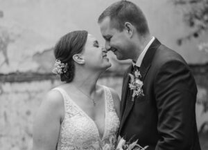 Portrait des Hochzeitspaares in schwarz/weiß wie sie lächelnd die Nasen aneinander reiben