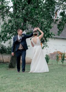 Braupaar tanzt auf der Wiese und der Bräutigam dreht seine Braut