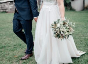 Nahaufnahme von gehenden Brautpaar mit Brautstrauß - das Brautpaar ist erst ab der Hüfte sichtbar