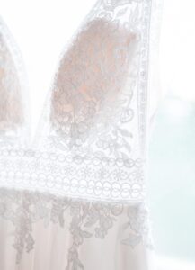 Seitliche Aufnahme des Brautkleides vor dem Fenster. Man sieht die wunderschönen Spitzendetails am Oberteil und den Übergang zum Rock