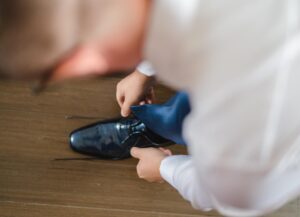 Bräutigam bindet sich die Schuhe zu. Aufnahme von oben über die Schulter