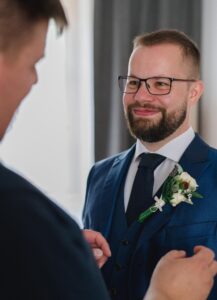 Trauzeuge steckt dem Bräutigam seinen Anstecken an