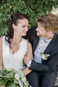 Braut und Bräutigam sitzen auf einer Bank und die beiden strahlen sich an