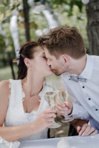 Braut und Bräutigam stoßen mit Sekt während der Agape an und küssen sich