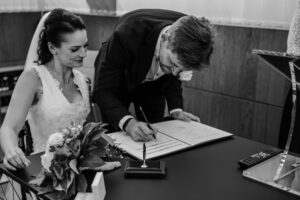 Der Bräutigam unterschreibt die Trauungsurkunde und strahlt