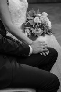 Nahaufnahme auf die Hände. Der Bräutigam hält liebevoll die Hand seiner Braut