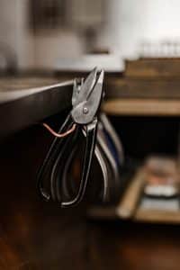 Nahaufnahme auf Werkzeug (Zangen) eines Goldschmieds. Die Zangen hängen auf der Seite seines Arbeitsplatzes