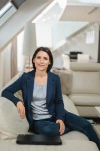 Portrait einer Anwältin im Rahmen einer Businessreportage in Wien. Sie sitzt auf der Bank und schaut dabei sehr sympathisch in die Kamera - vor ihr liegt ihr Laptop