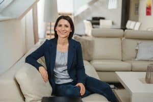 Portrait einer Anwältin im Rahmen einer Businessreportage in Wien. Sie sitzt auf der Bank und schaut dabei sehr sympathisch in die Kamera - vor ihr liegt ihr Laptop