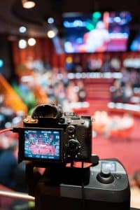 Buinessreportage_Veranstaltungsreporte: Live Video Podcast von Corinna Hintenberger mit Stefan Verra im socialhub Wien. Close Up auf die Kamera welche den Podcast mitfilmt. Am Bildschirm der Kamera sieht man das Aufnahmestudio in dem Corinna Hintenberger & Stefan Verra sitzen - rundherum das Publikum. Der Hintergrund ist unscharf