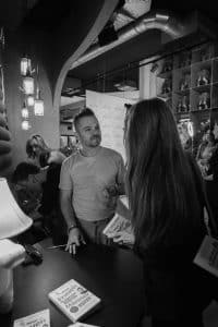Buinessreportage_Veranstaltungsreporte: Live Video Podcast von Corinna Hintenberger mit Stefan Verra im socialhub Wien. Schwarz/weiß-Aufnahme von Stefan Verra - er signiert nach der Veranstaltung sein Buch und unterhält sich dabei mit dem Publikum. Dabei hört er genau zu was seine Fans sagen