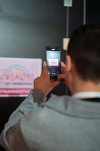 Buinessreportage_Veranstaltungsreporte: Live Video Podcast von Corinna Hintenberger mit Stefan Verra im socialhub Wien. Vorbereitung der Veranstaltung.Daniel Zieser fotografiert mit seinem Handy die Beschilderung "Business mit Himbeersaft - Aufnahmestudio"