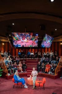 Buinessreportage_Veranstaltungsreporte: Live Video Podcast von Corinna Hintenberger mit Stefan Verra im socialhub Wien. Stefan Verra ist aufgestanden und bewegt sich im Raum - hin zu den Zuschauer*innen und beantwortet Publikumsfragen